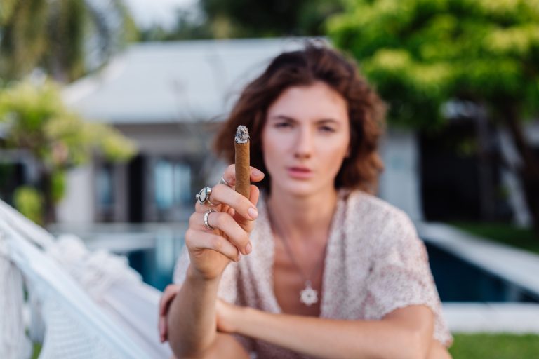Donna che fuma un sigaro sdraiata su un'amaca